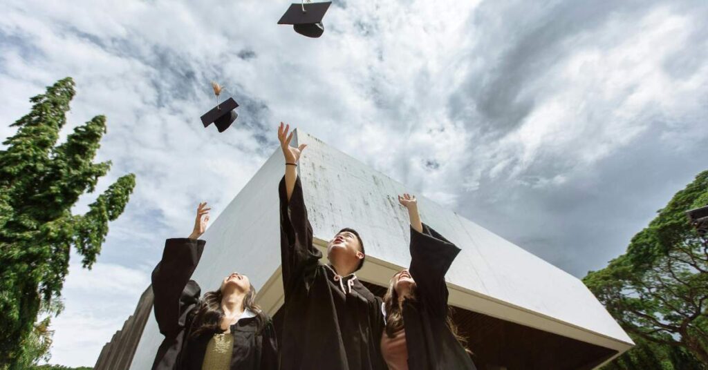 Graduates in graduation gowns throwing their caps in the air