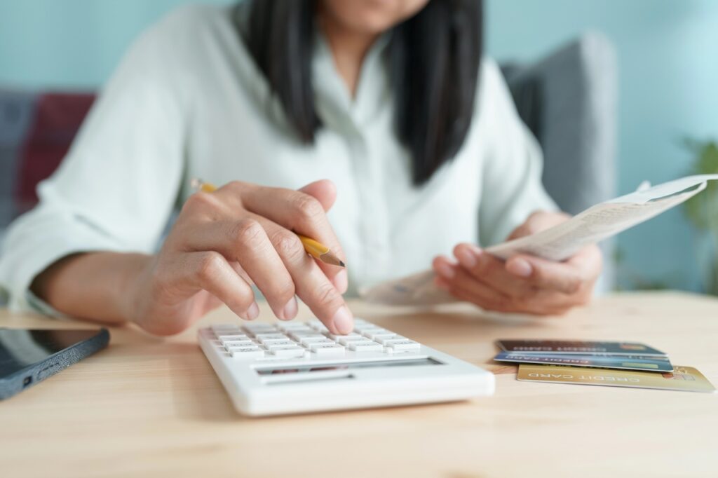 Hand of Asian woman are calculating costs and payments. Source: The College Investor