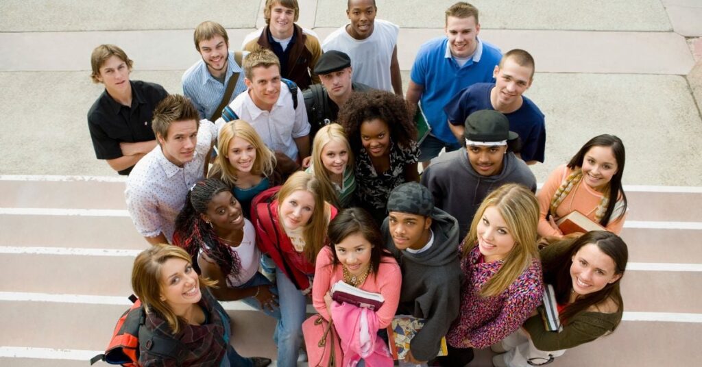 A group of students standing on white steps looking up at the camera